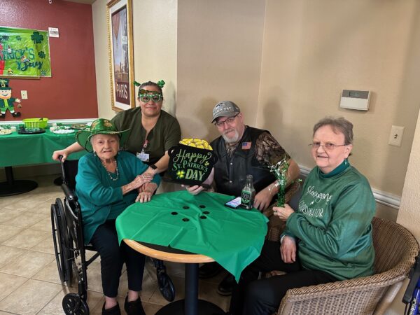 Four elderly friends from assisted living living option sitting around a table smiling 